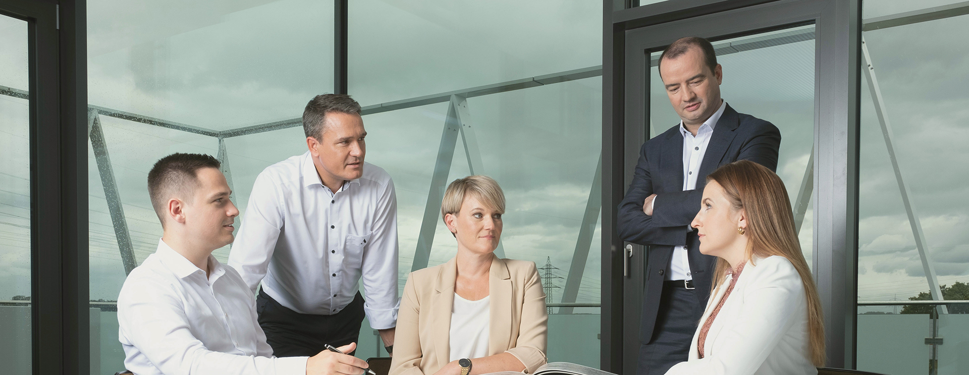 Ein Team von Azemos, einer bankenunabhängigen Vermögensverwaltung, bei einer Beratungssitzung in einem modernen Büro mit großen Fenstern.