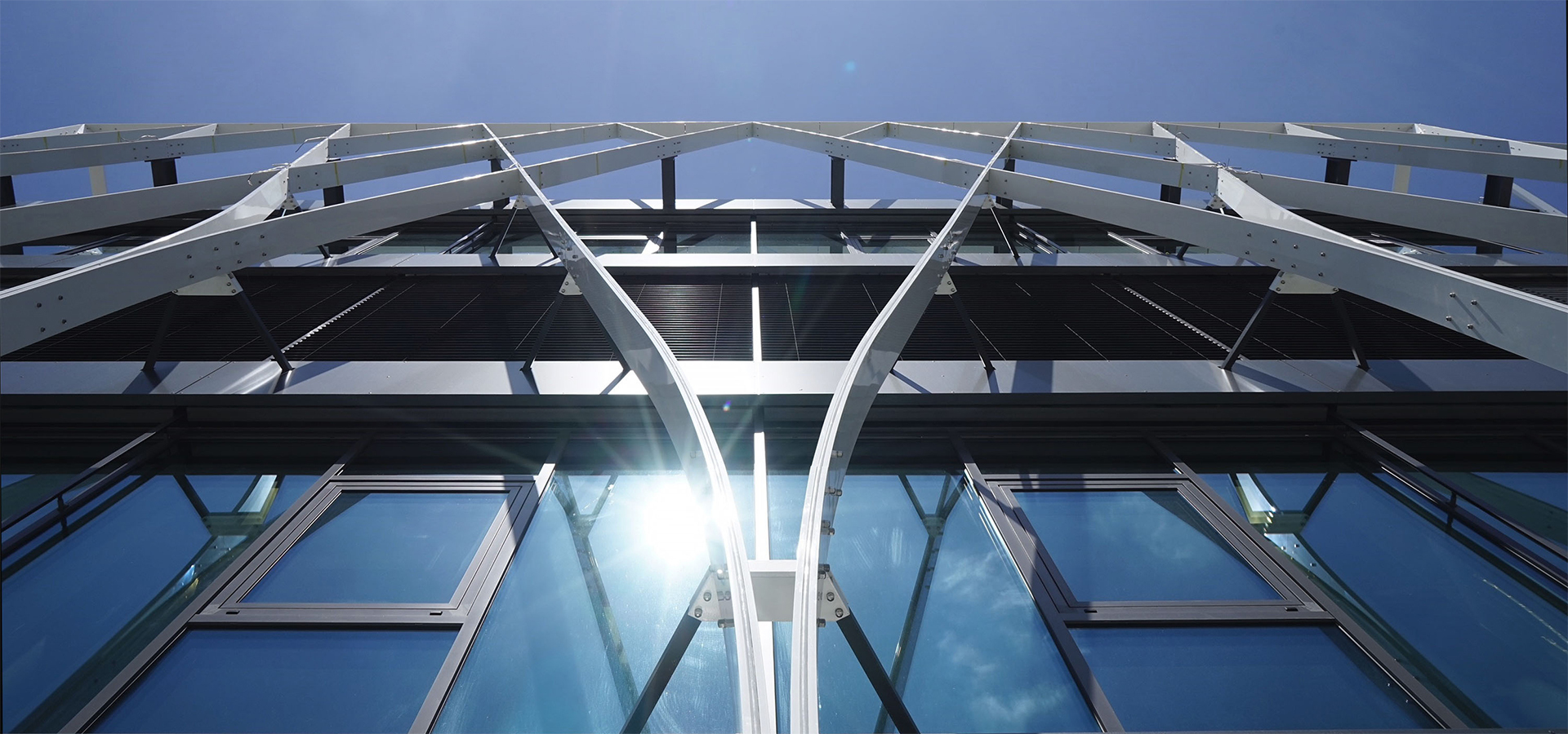 Moderne Fassade eines Bürogebäudes mit metallenen Tragstrukturen und Glasflächen, die Transparenz und Professionalität symbolisieren – passend zum konservativen, verantwortungsvollen Ansatz von Azemos, einer unabhängigen Vermögensverwaltung.